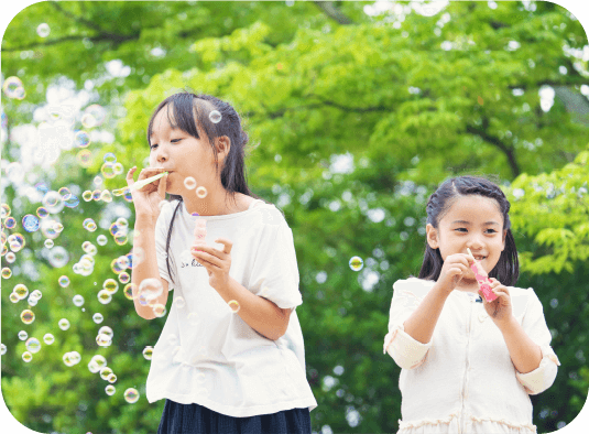 写真：女の子2人がシャボン玉を吹いて遊んでいる